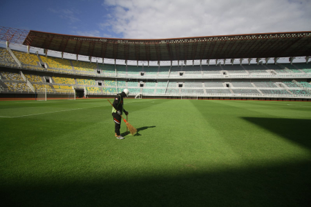 Pekerja menyapu rumput kering di Stadion Gelora Bung Tomo